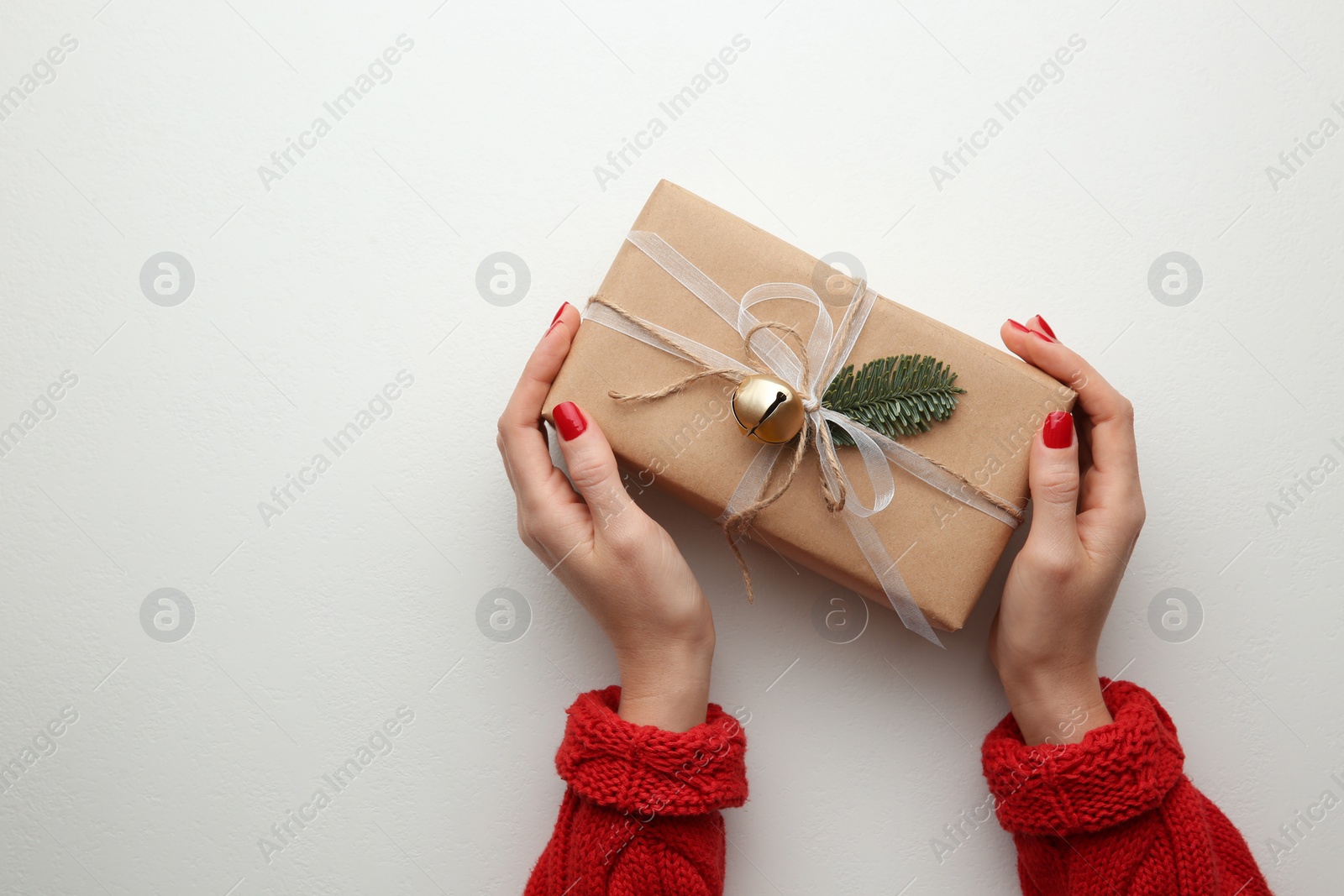 Photo of Woman holding Christmas gift box on white background, top view. Space for text