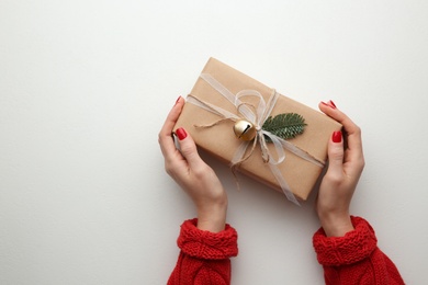 Woman holding Christmas gift box on white background, top view. Space for text