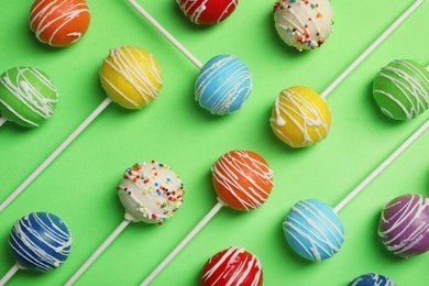 Photo of Bright delicious cake pops on color background, flat lay