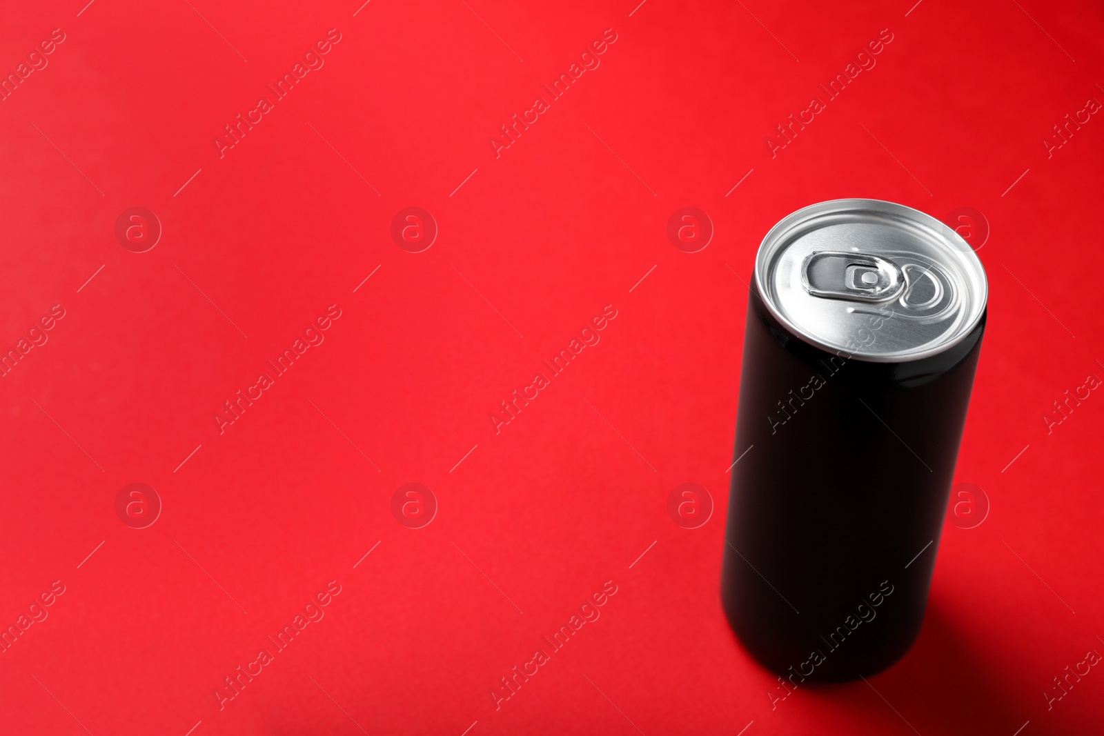 Photo of Black can of energy drink on red background. Space for text