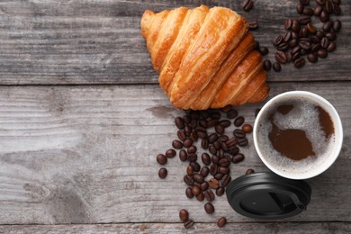 Coffee to go. Paper cup of tasty drink, croissant and beans on wooden table, flat lay with space for text
