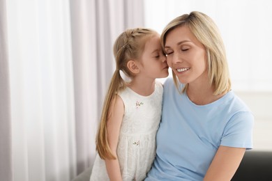 Photo of Daughter kissing her happy mother at home. Space for text