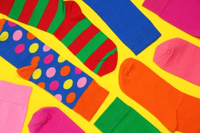 Many different colorful socks on yellow background, flat lay