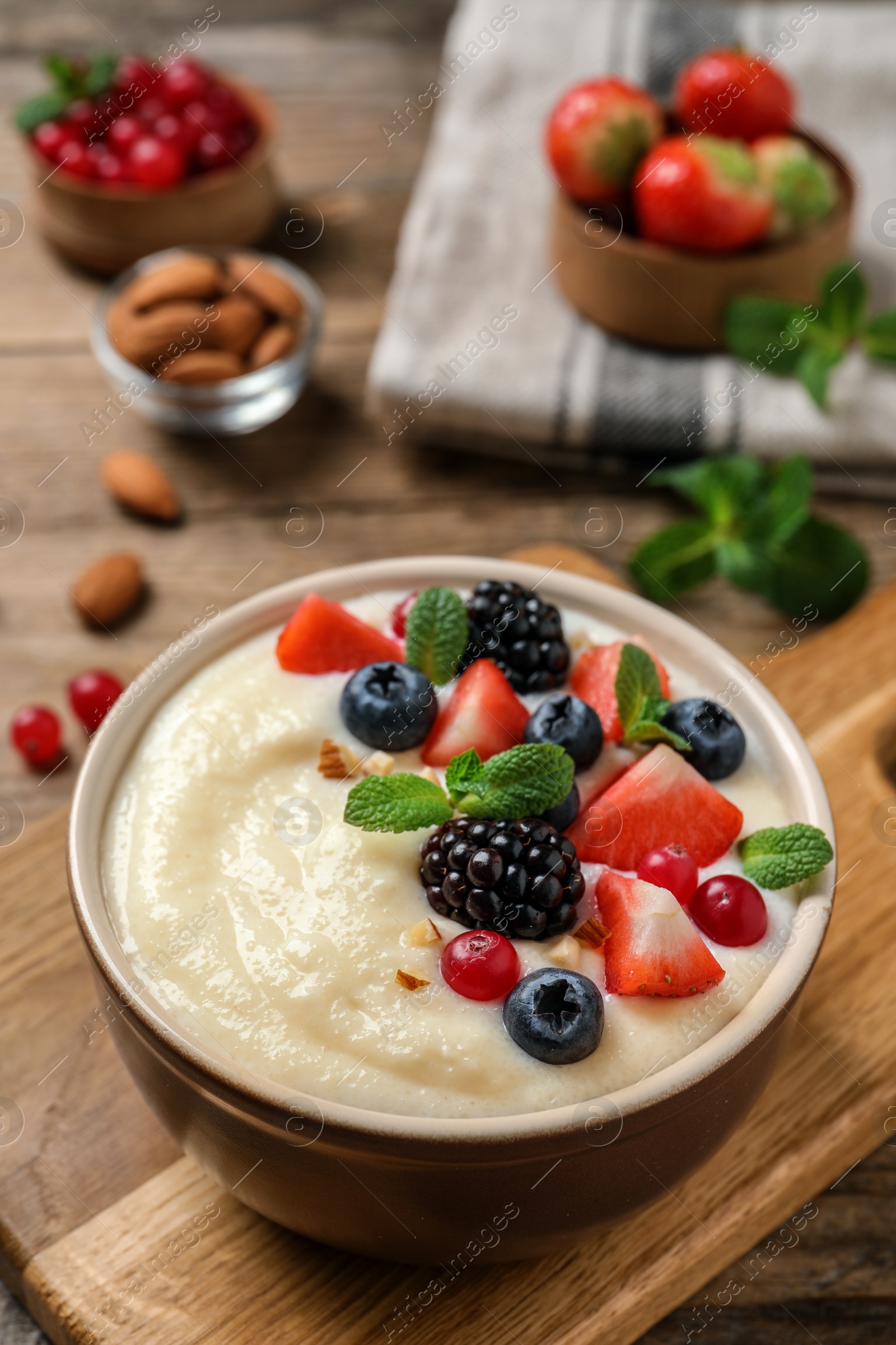 Photo of Delicious semolina pudding with berries on wooden table