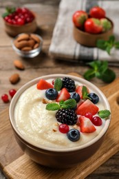 Photo of Delicious semolina pudding with berries on wooden table