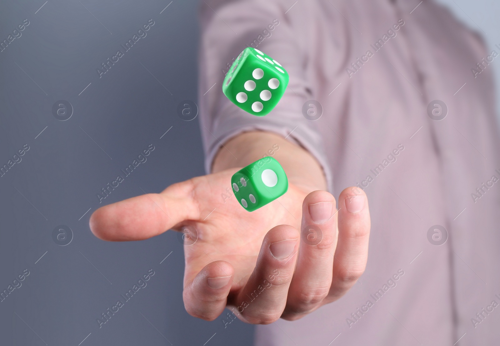 Image of Man throwing green dice on grey background, closeup