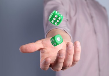 Image of Man throwing green dice on grey background, closeup