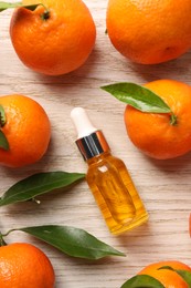 Bottle of tangerine essential oil and fresh fruits on white wooden table, flat lay