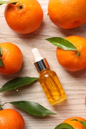 Photo of Bottle of tangerine essential oil and fresh fruits on white wooden table, flat lay