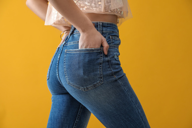 Photo of Woman wearing jeans on yellow background, closeup