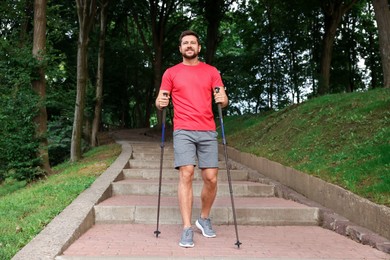 Man practicing Nordic walking with poles on steps outdoors