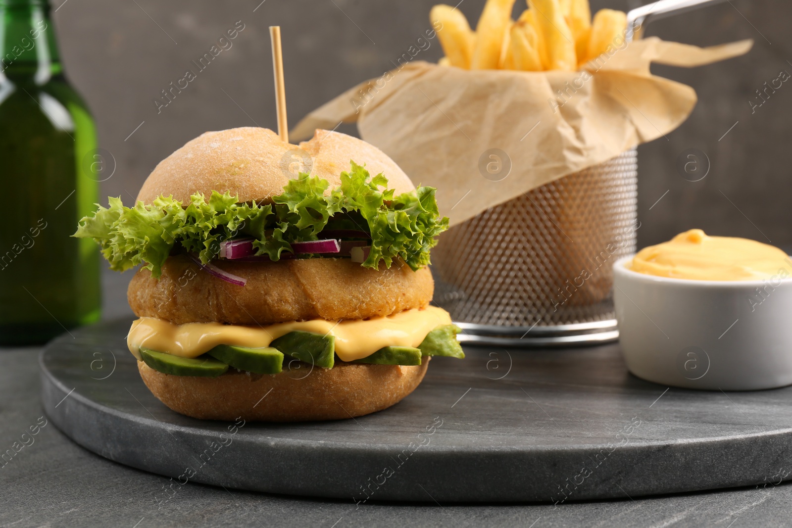 Photo of Tasty vegetarian burger with cutlet, cheese, avocado and onion on black table, closeup. Space for text