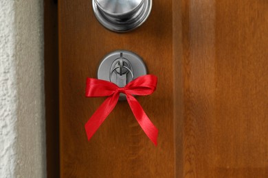 Photo of House key with red bow in door lock, closeup. Housewarming party