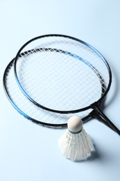 Feather badminton shuttlecock and rackets on light blue background