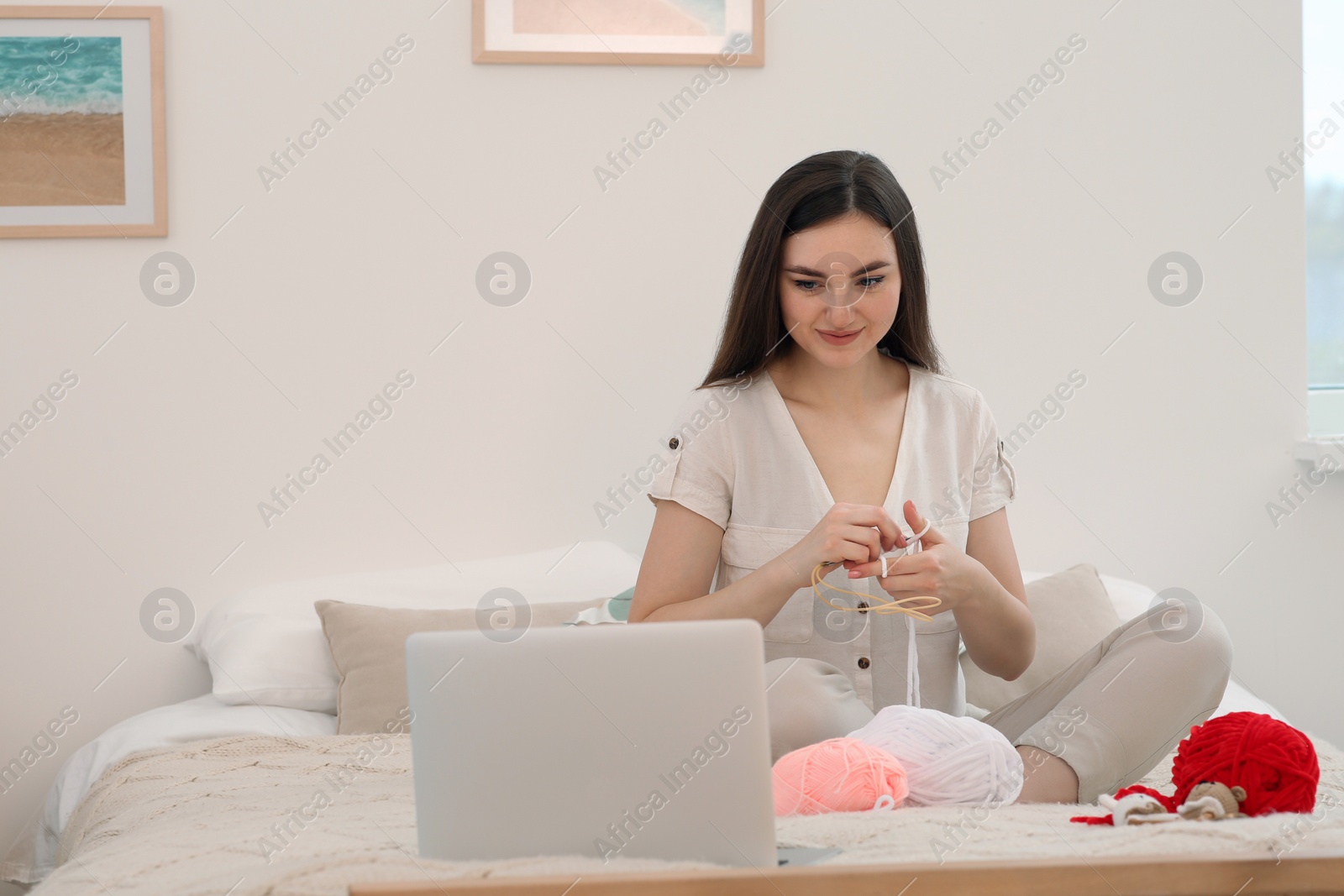 Photo of Young woman learning to knit with online course at home, space for text. Handicraft hobby