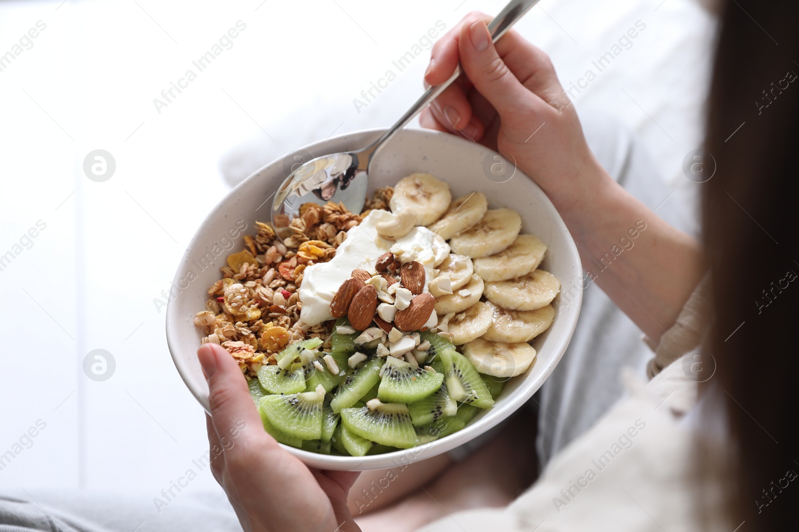 Photo of Woman eating tasty granola indoors, closeup view