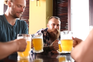 Photo of Friends drinking beer at table in pub