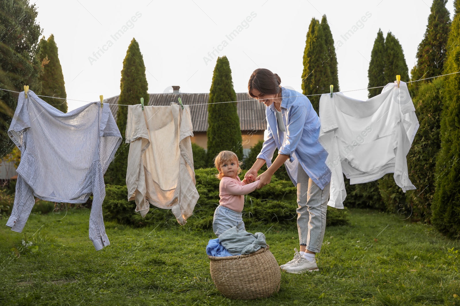 Photo of Mother and daughter near washing line with drying clothes in backyard