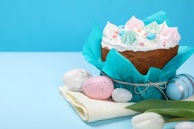 Photo of Traditional Easter cake with meringues and painted eggs on light blue background, space for text