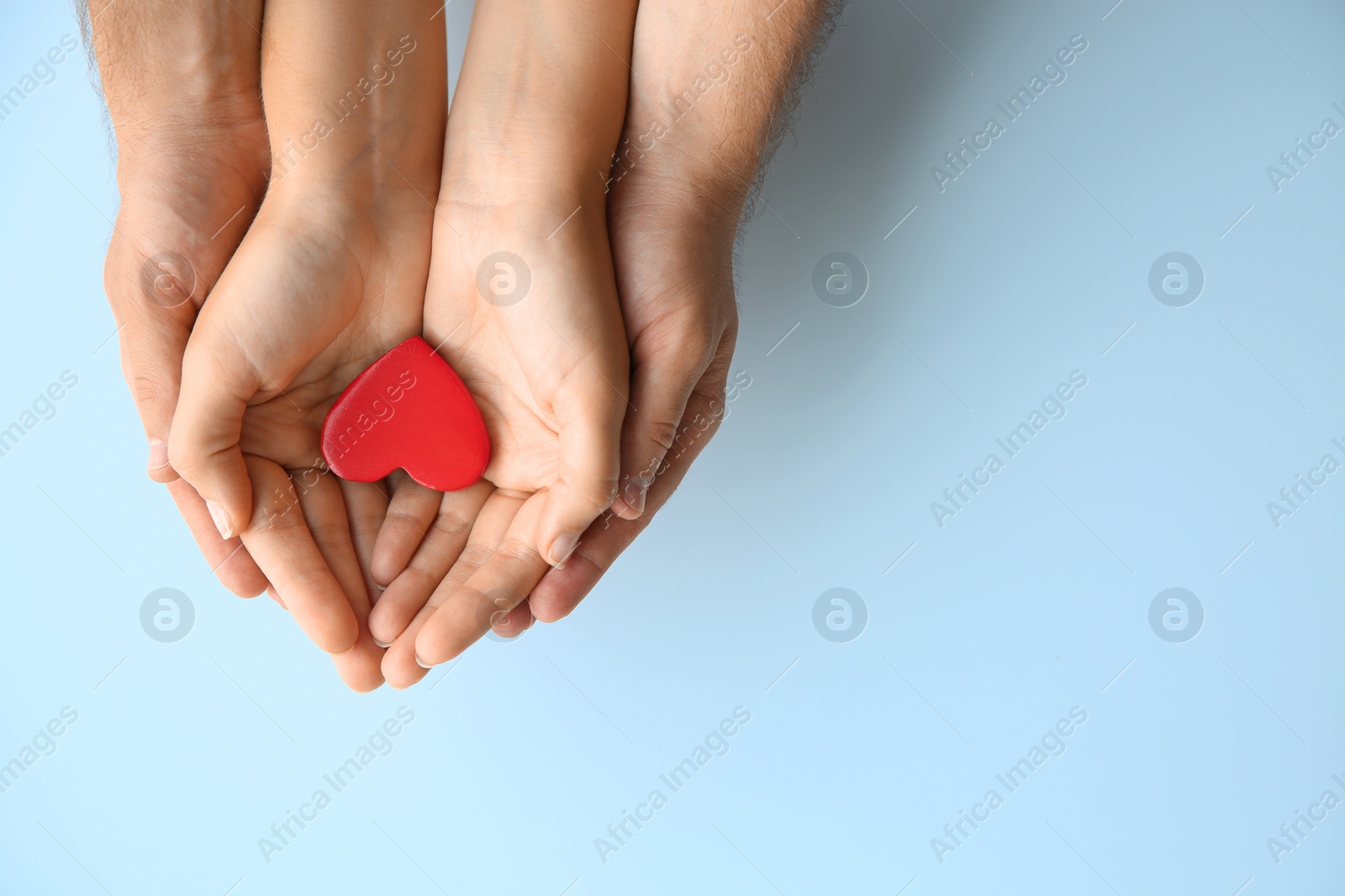 Photo of Young couple with red heart on white background, top view