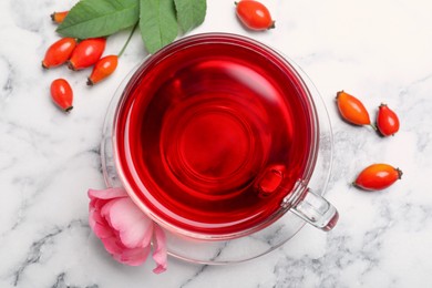 Photo of Fresh rose hip tea and berries on white marble table, flat lay