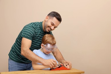 Father teaching son how to work with plane near beige wall