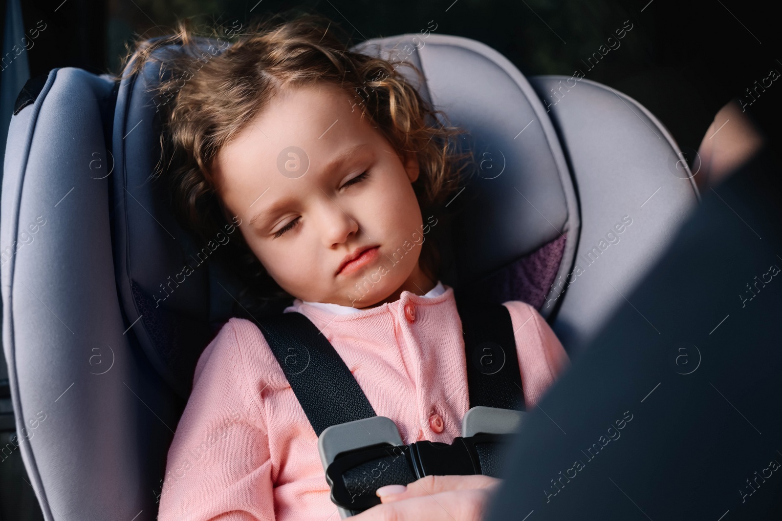 Photo of Cute little girl sleeping in child safety seat inside car