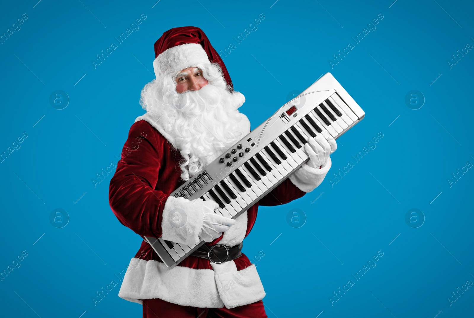 Photo of Santa Claus with synthesizer on blue background. Christmas music