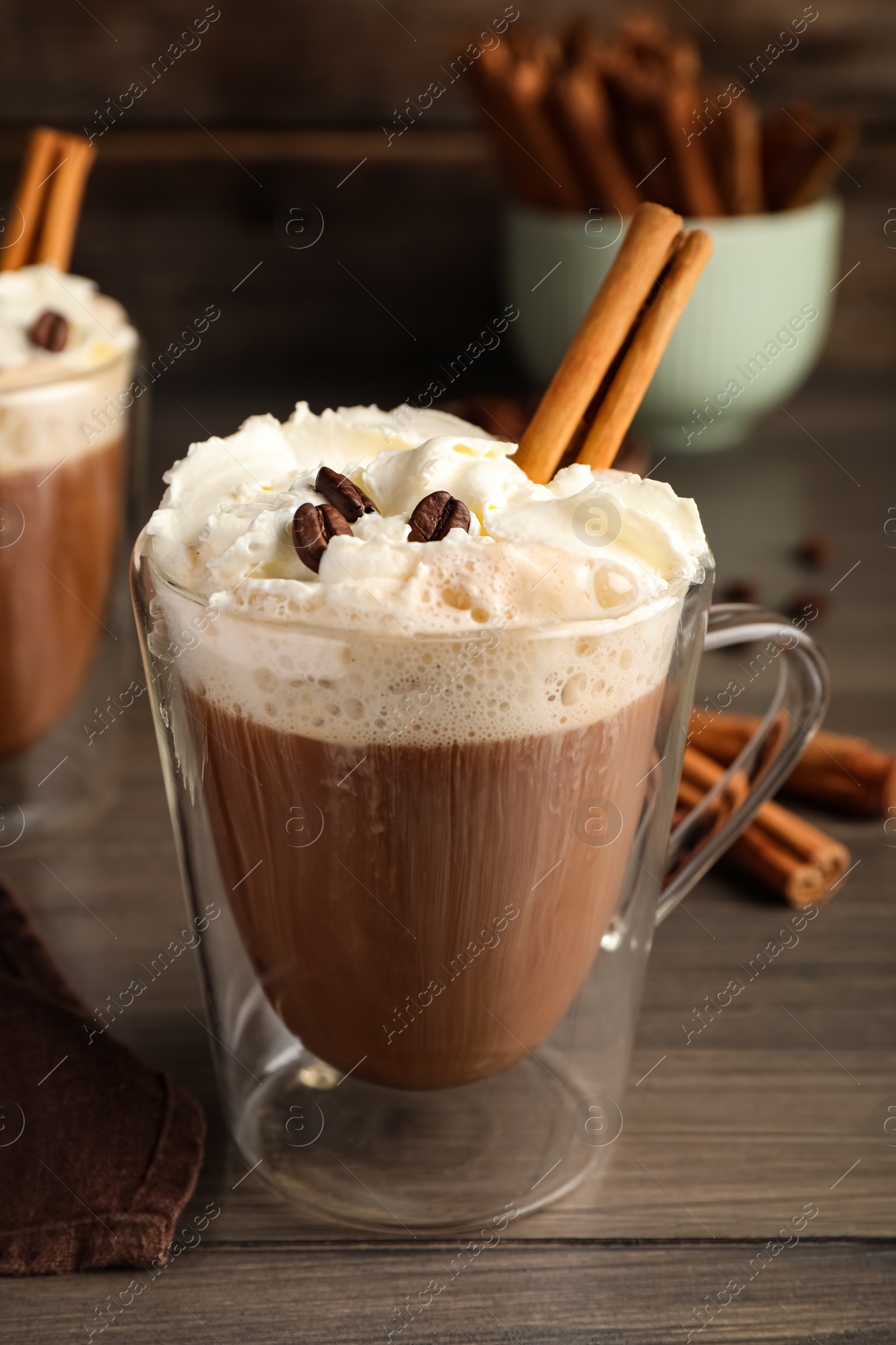 Photo of Delicious coffee with whipped cream and cinnamon on wooden table