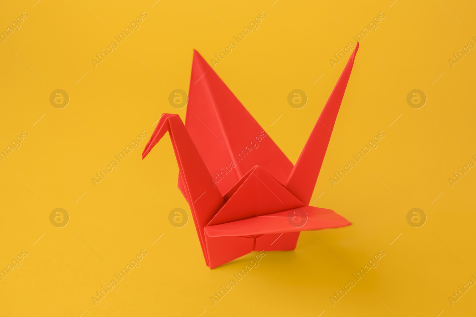 Photo of Origami art. Beautiful red paper crane on orange background