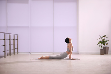 Young woman practicing cobra asana in yoga studio. Bhujangasana pose