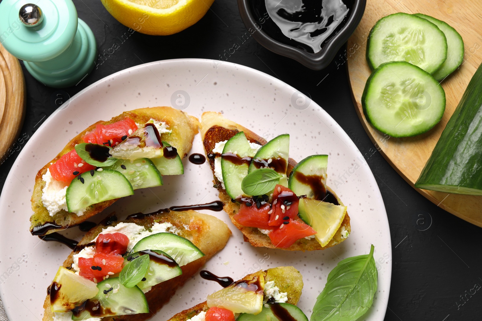 Photo of Delicious bruschettas with balsamic vinegar, toppings and products on dark table, flat lay