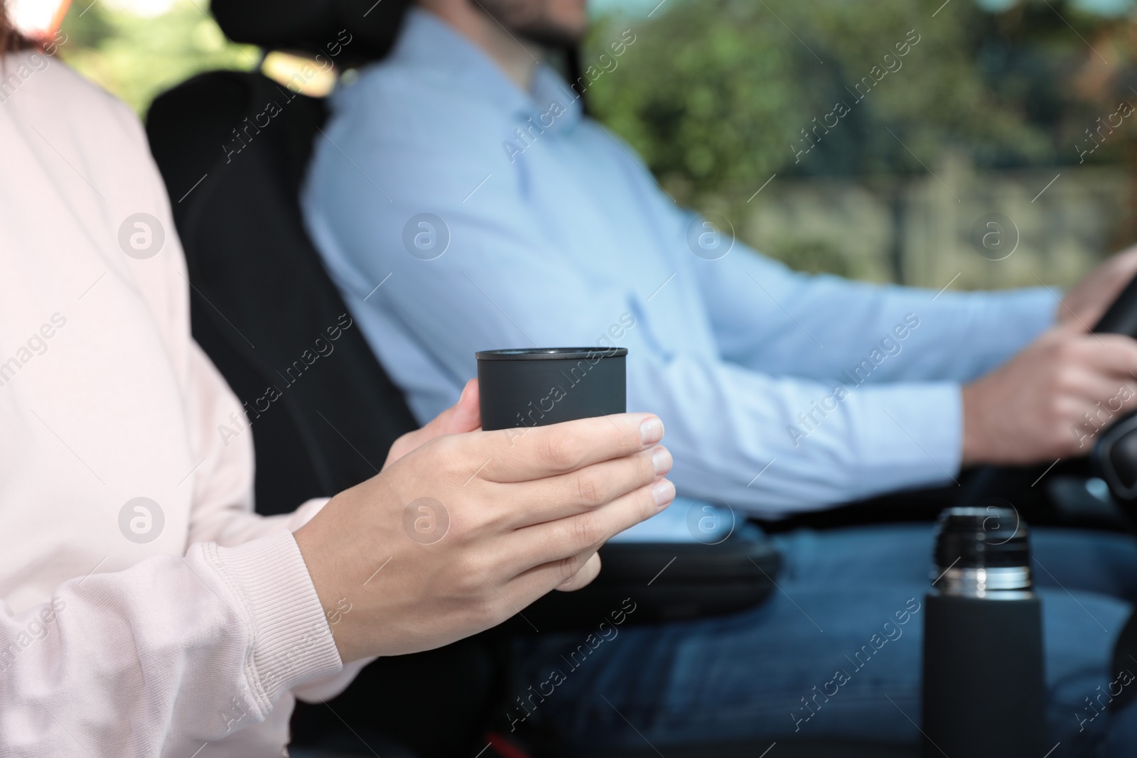 Photo of Woman with thermos cap on passenger seat of car, closeup