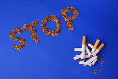 Word Stop made of dry tobacco and broken cigarettes on blue background, flat lay. Quitting smoking concept