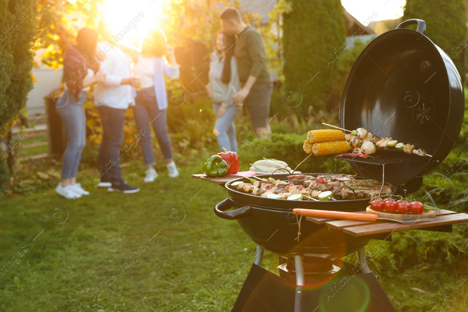 Photo of Group of friends having party outdoors. Focus on barbecue grill with food. Space for text