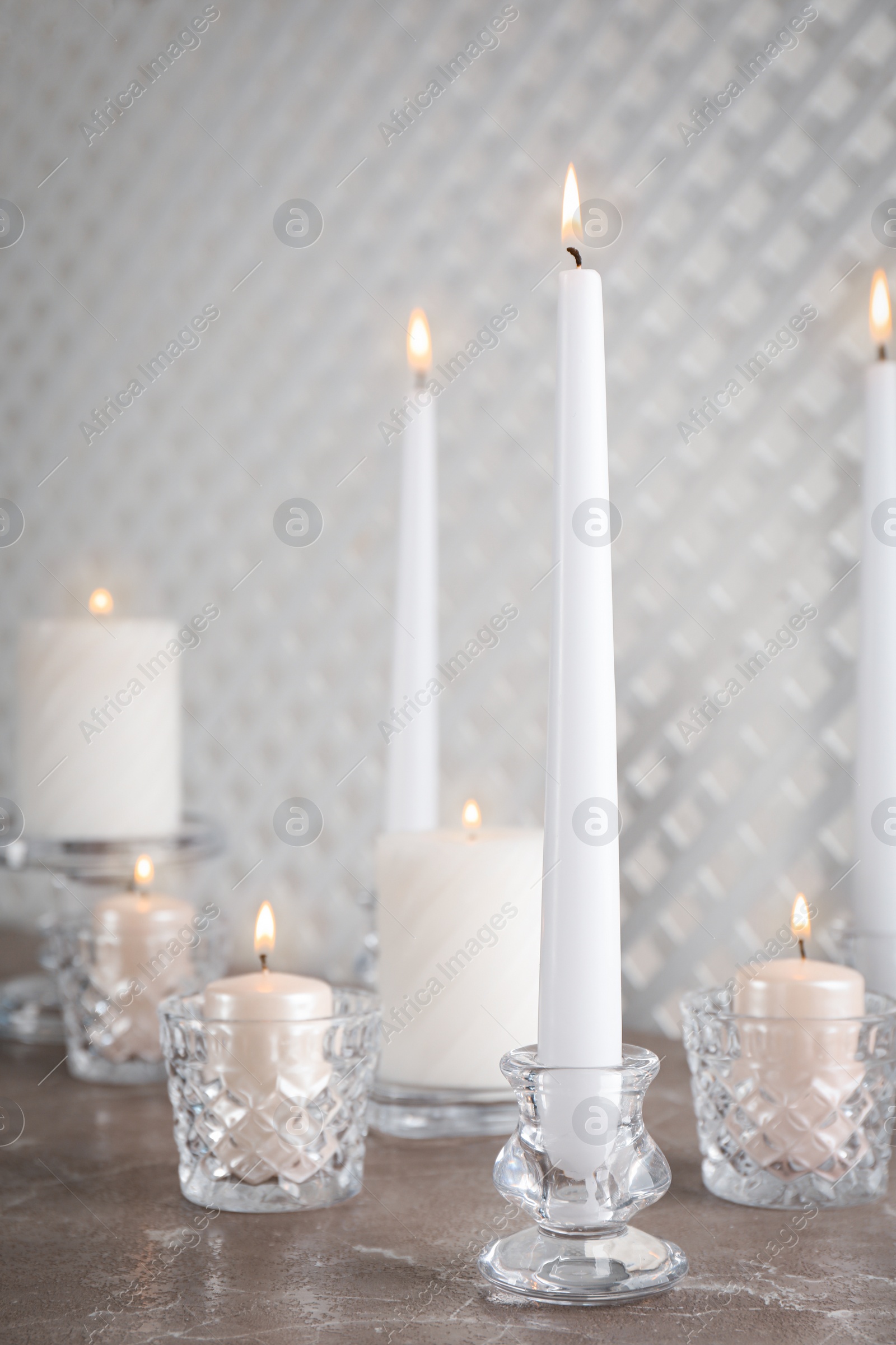 Photo of Elegant candlesticks with burning candles on marble table