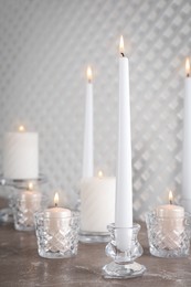 Elegant candlesticks with burning candles on marble table