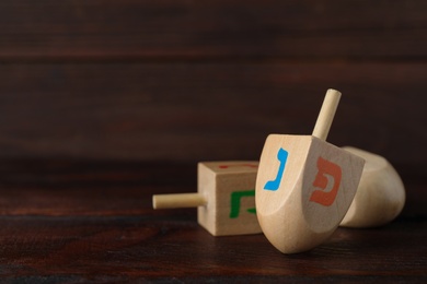 Photo of Hanukkah traditional dreidel with letters Nun and Pe on wooden table. Space for text