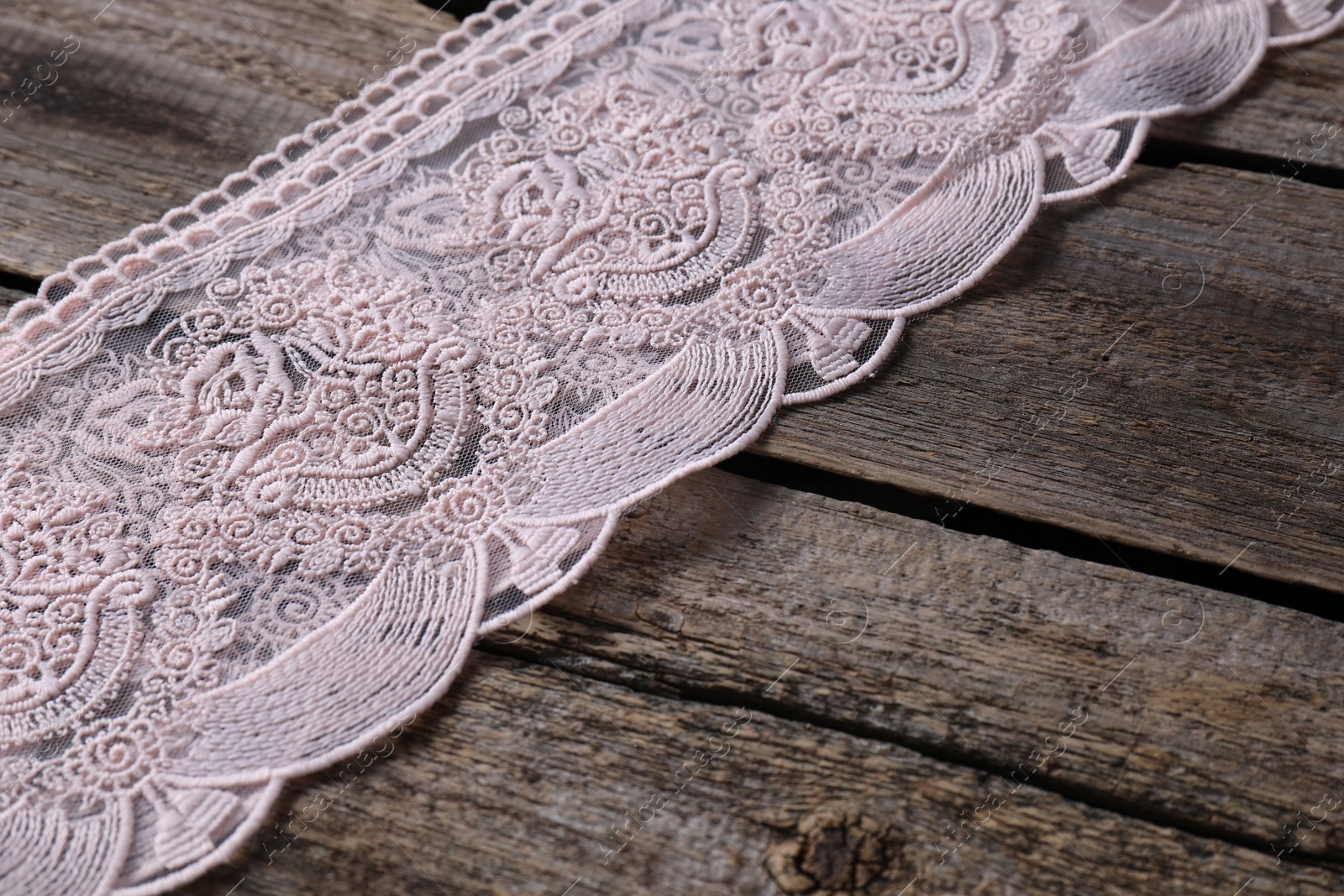 Photo of Pink lace with beautiful pattern on wooden table, closeup