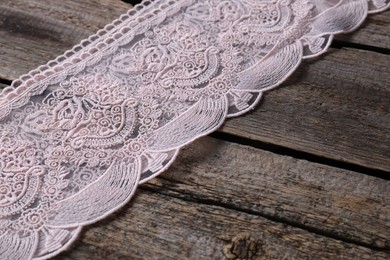 Pink lace with beautiful pattern on wooden table, closeup