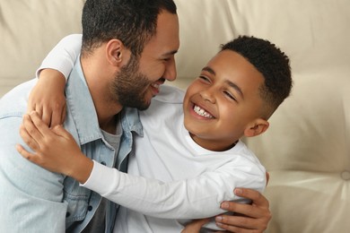 Photo of Father with his African American son on sofa. International family