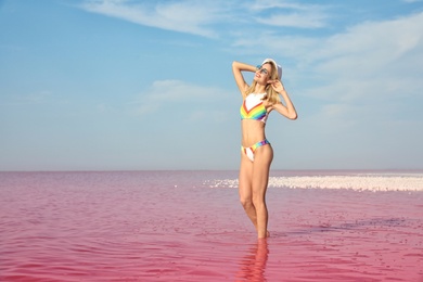 Beautiful woman posing in pink lake on sunny day
