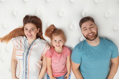 Photo of Happy family lying on new orthopedic mattress, top view