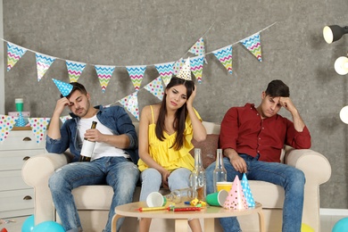 Photo of Friends suffering from hangover in messy room after party