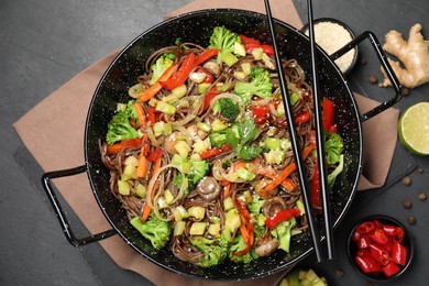 Photo of Wok with noodles, mushrooms, vegetables and other products on black table, flat lay