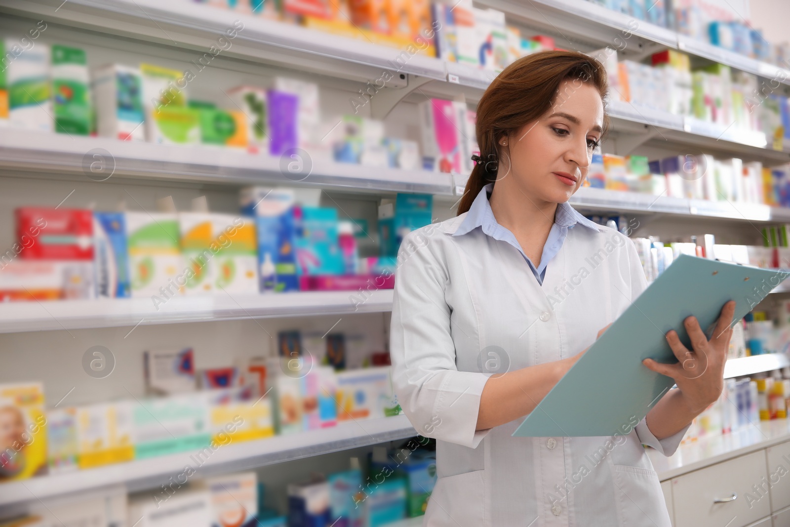 Photo of Professional pharmacist with clipboard in modern drugstore