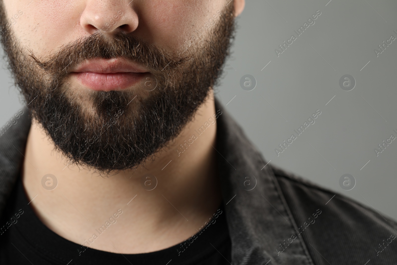 Photo of Handsome young man with mustache on grey background, closeup