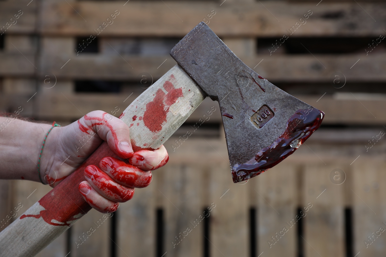 Photo of Man holding bloody axe outdoors, closeup view