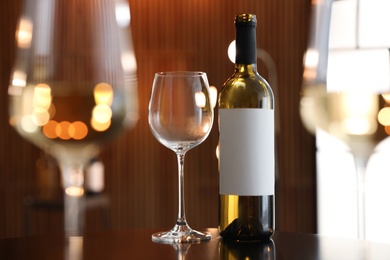 Bottle and glasses of wine on table against blurred background. Space for text