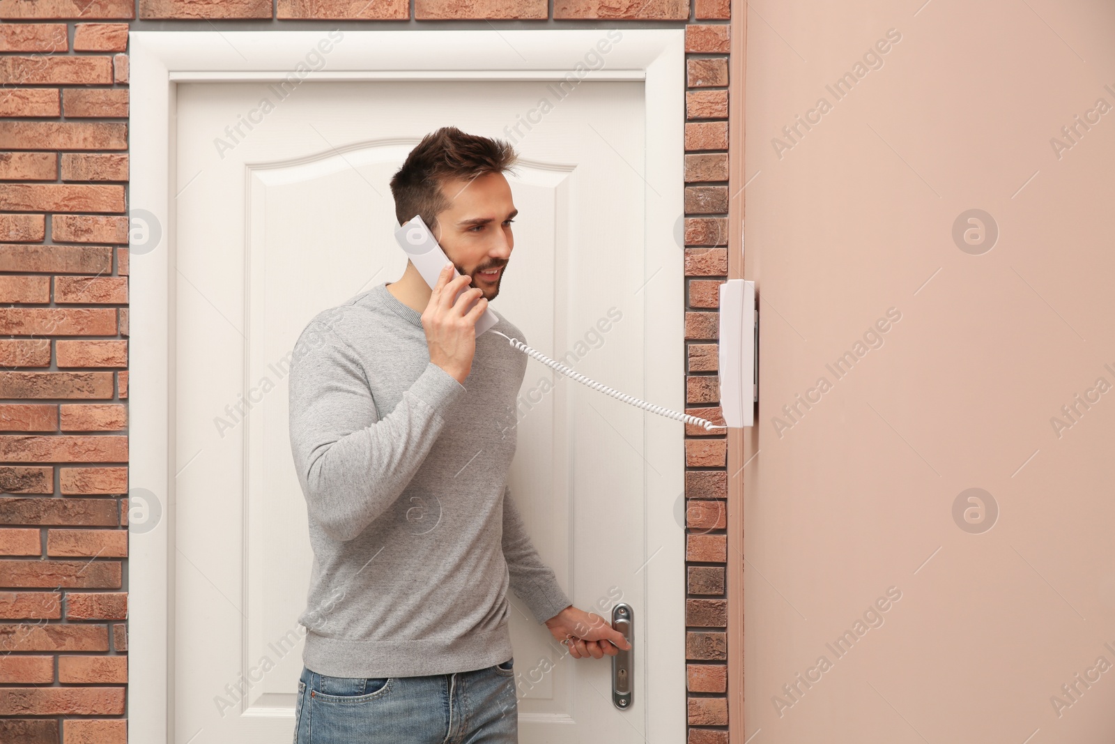 Photo of Man with handset answering intercom call indoors